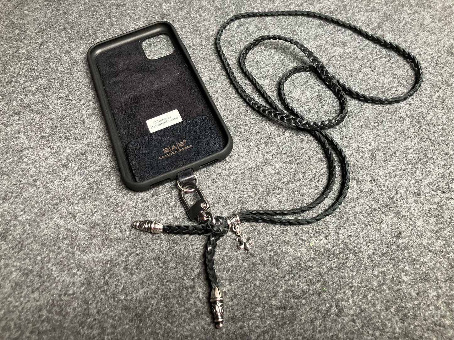 Capa/Suporte para iPhone de Couro Flor Integral/microfibra. 2 Terminais Espirais, 1 Pino em Espiral com Argola e 1 Pingente Fleur de Lys, todos de Prata 925 & Crossbody/Colar/Pulseira de Couro com 3 fios duplos trançados à mão, Marrom ou Preto.- KC45i