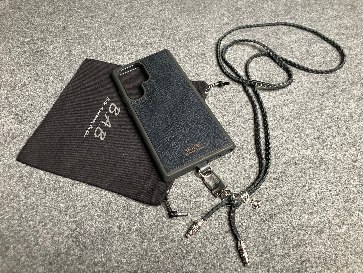 Capa/Suporte para Samsung de Couro Flor Integral/microfibra. 2 Terminais Espirais, 1 Pino em Espiral com Argola e 1 Pingente Fleur de Lys, todos de Prata 925 & Crossbody/Colar/Pulseira de Couro com 3 fios duplos trançados à mão, Marrom ou Preto.- KC45S