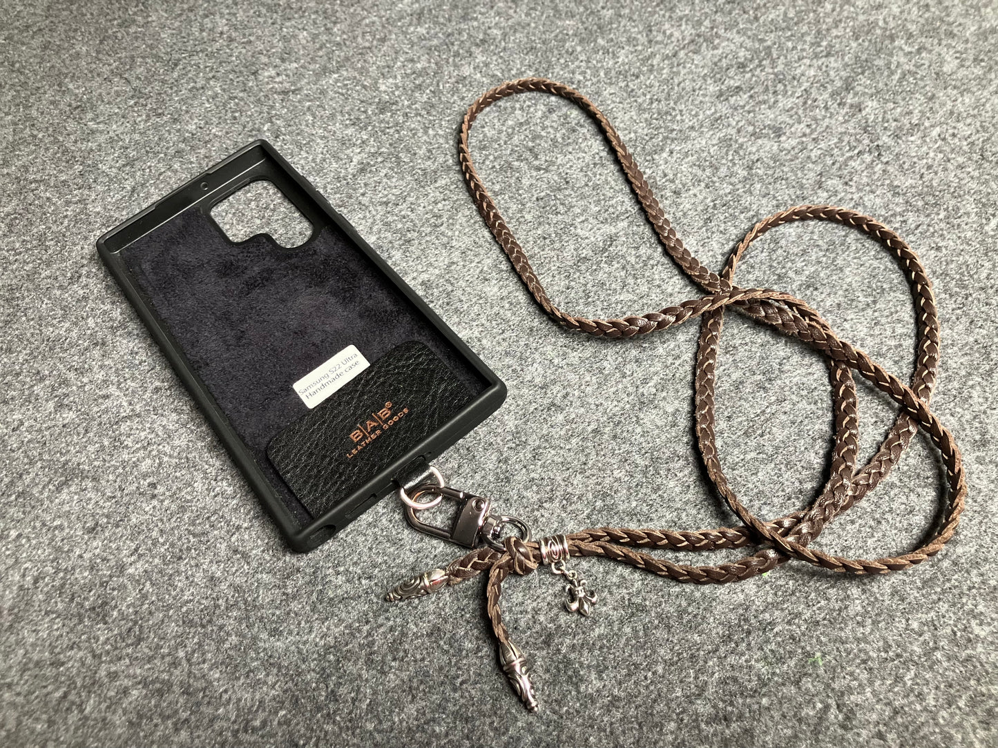 Capa/Suporte para Samsung de Couro Flor Integral/microfibra. 2 Terminais Espirais, 1 Pino em Espiral com Argola e 1 Pingente Fleur de Lys, todos de Prata 925 & Crossbody/Colar/Pulseira de Couro com 3 fios duplos trançados à mão, Marrom ou Preto.- KC45S