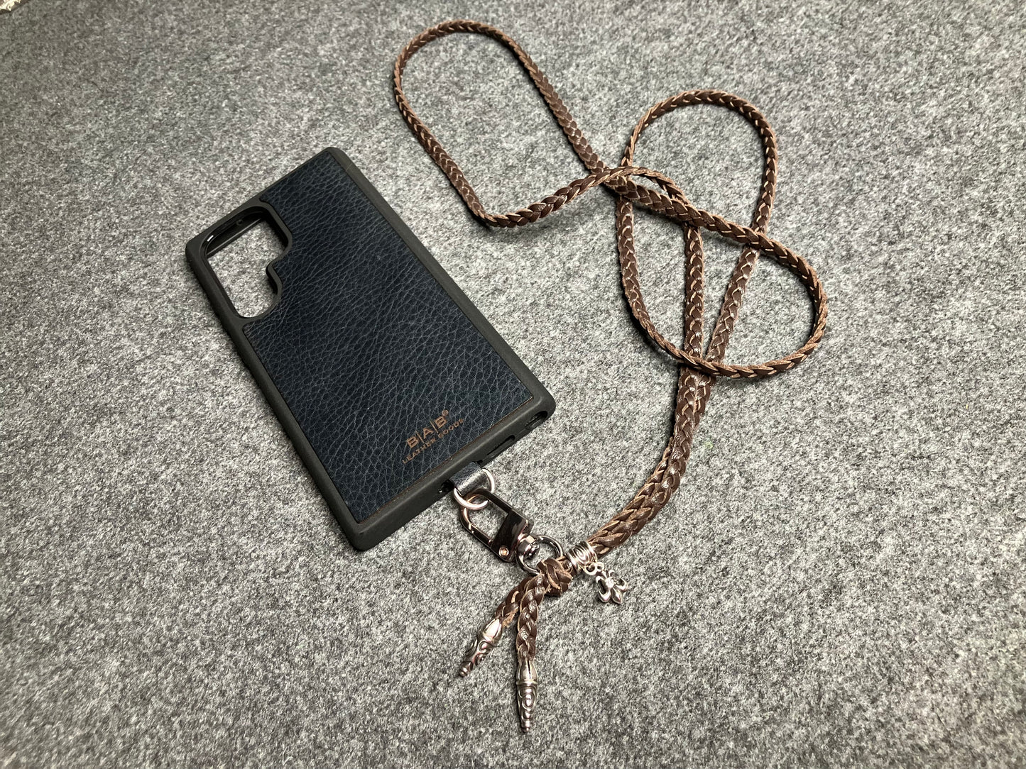 Capa/Suporte para Samsung de Couro Flor Integral/microfibra. 2 Terminais Espirais, 1 Pino em Espiral com Argola e 1 Pingente Fleur de Lys, todos de Prata 925 & Crossbody/Colar/Pulseira de Couro com 3 fios duplos trançados à mão, Marrom ou Preto.- KC45S