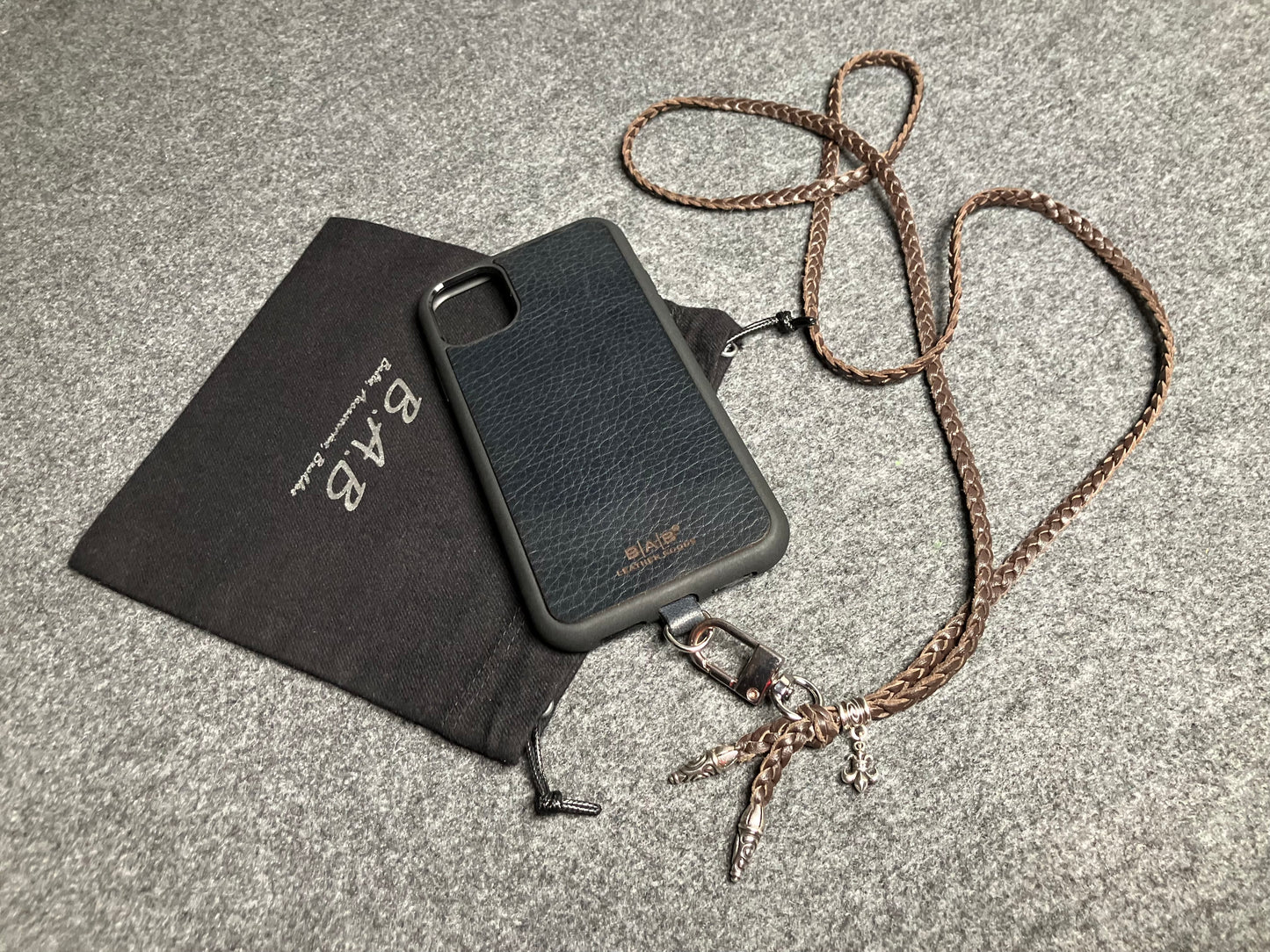 Capa/Suporte para iPhone de Couro Flor Integral/microfibra. 2 Terminais Espirais, 1 Pino em Espiral com Argola e 1 Pingente Fleur de Lys, todos de Prata 925 & Crossbody/Colar/Pulseira de Couro com 3 fios duplos trançados à mão, Marrom ou Preto.- KC45i