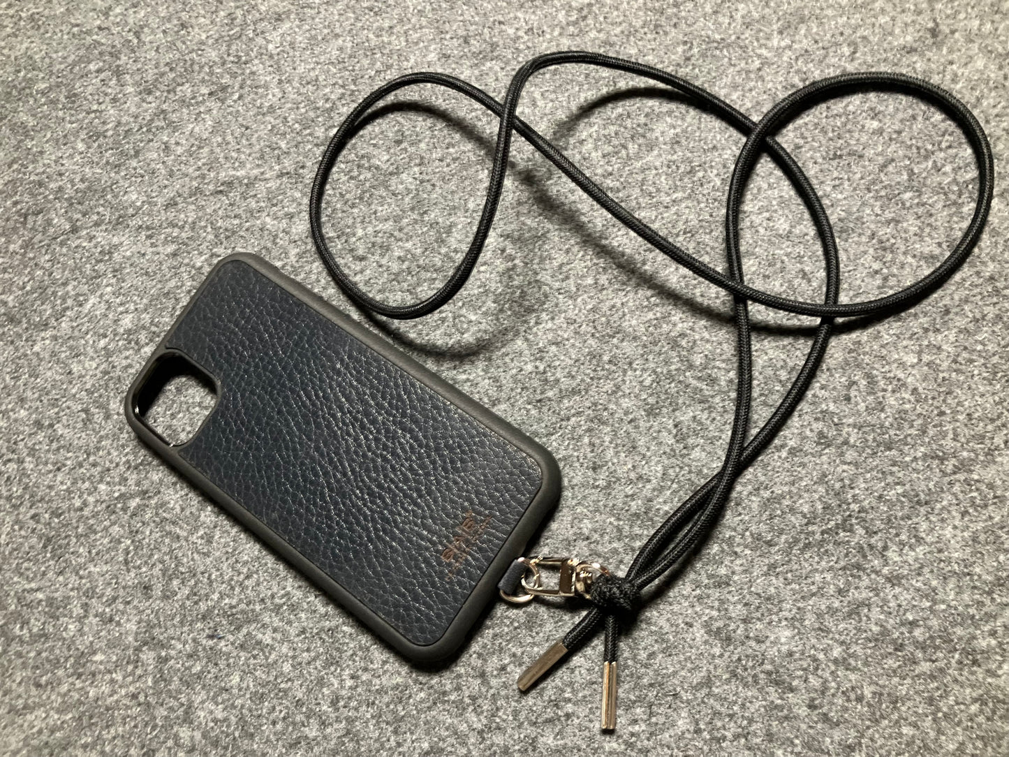 Support pour téléphone portable en Cuir Véritable Pleine Fleur tanné végétal au tanin gravé au laser & Bandoulière/Collier/Bracelet Cordon Élastique Noir, avec 1 Mousqueton et 2 Embouts argentés.- SC57