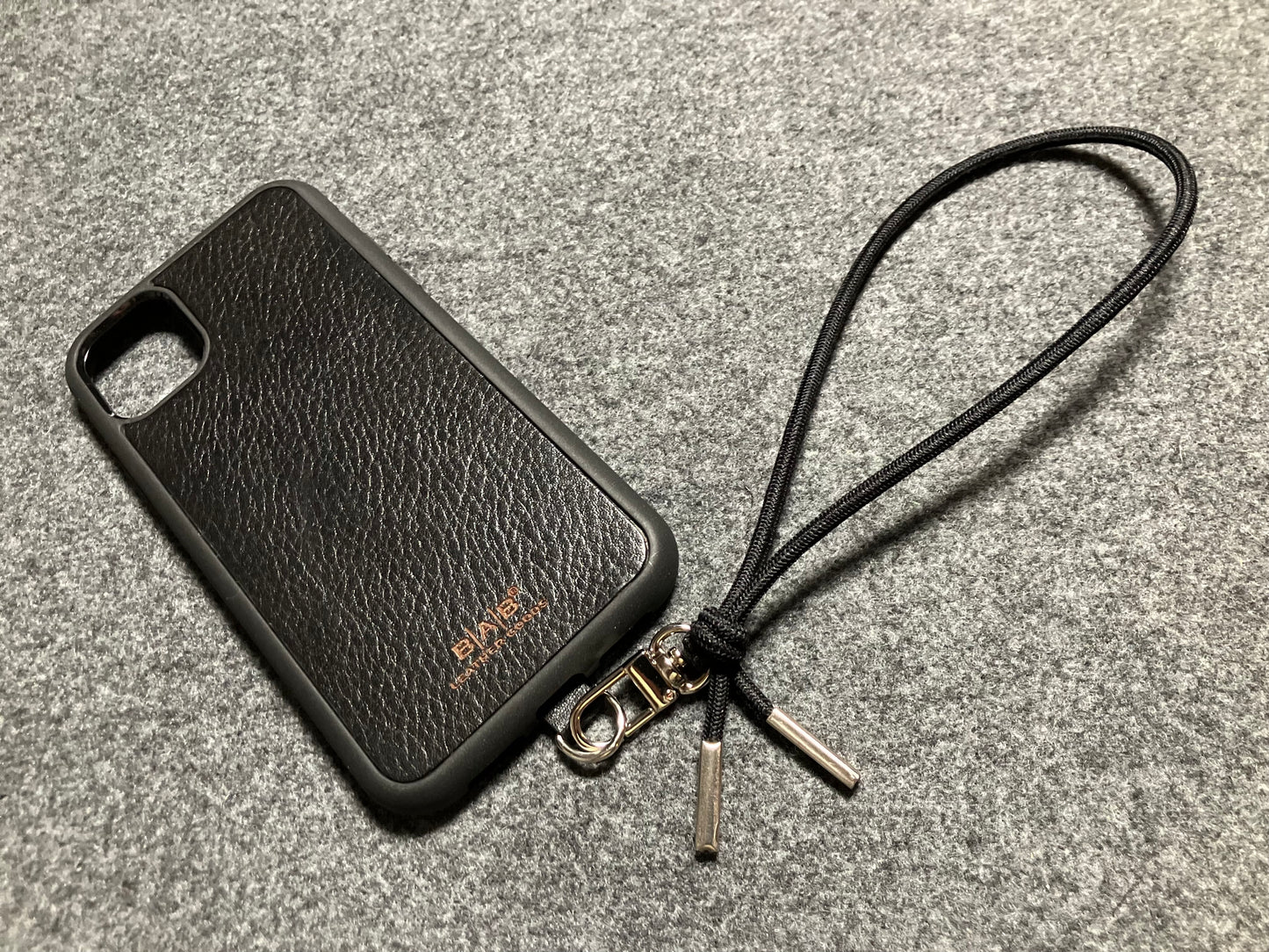 Capa/Suporte para iPhone de Couro Genuíno Flor Integral curtido vegetal com tanino cortados e gravados a laser/microfibra & Correia/Pulseira de Corda Elástica Preta com 1 Mosquetão e 2 Terminais prateados.- KPi54 