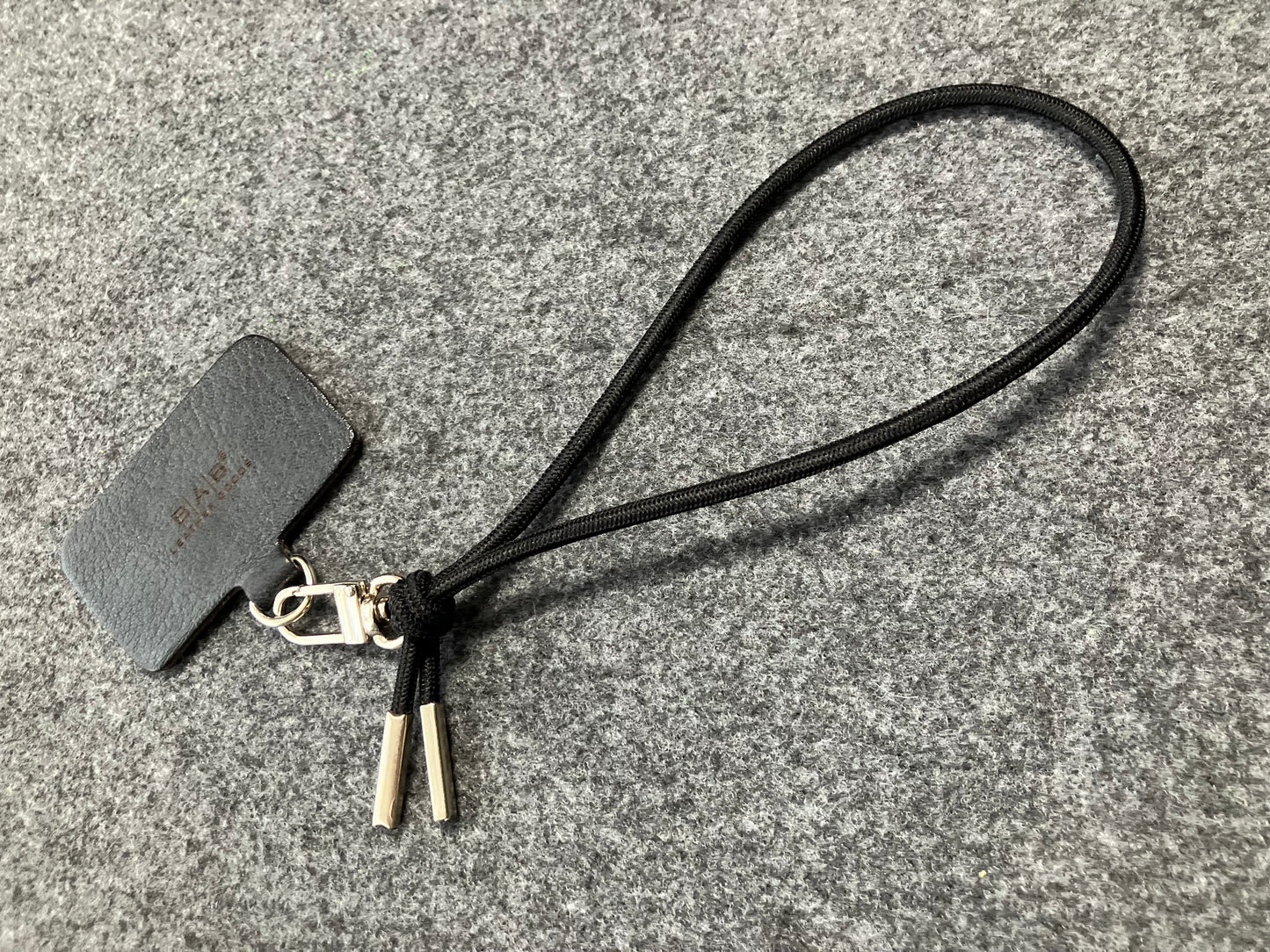 Laser-engraved Full-Grain vegetable-tanned Genuine Leather cell phone Holder & Black Elastic Rope Strap/Bracelet with a Carabiner, and 2 Silver End caps.- SP56