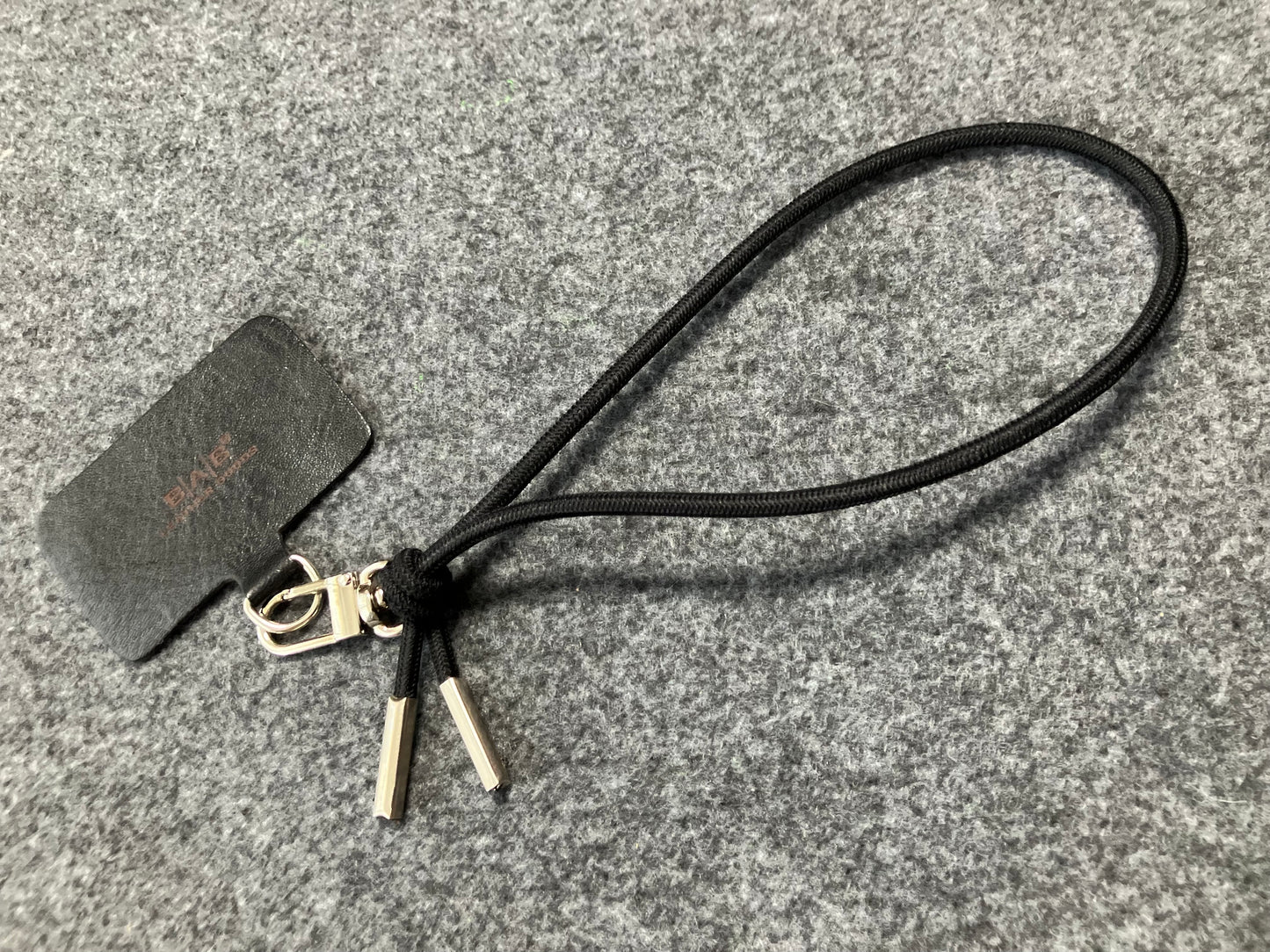 Laser-engraved Full-Grain vegetable-tanned Genuine Leather cell phone Holder & Black Elastic Rope Strap/Bracelet with a Carabiner, and 2 Silver End caps.- SP56