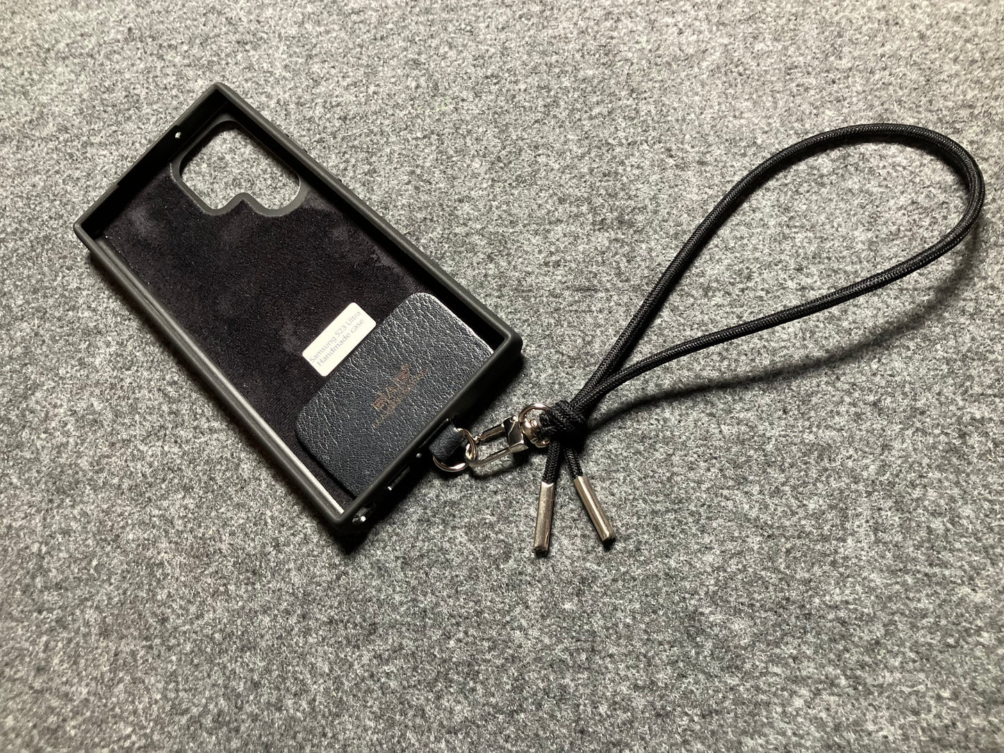 Θήκη/Στήριγμα για Samsung, από Γνήσιο Δέρμα Oλικής άλεσης κομμένο και χαραγμένο με λέιζερ/μικροΐνα & Μαύρο Ελαστικό Σχοινί Λουράκι/Βραχιόλι με 2 Aσημένια άκρα.- KPS55